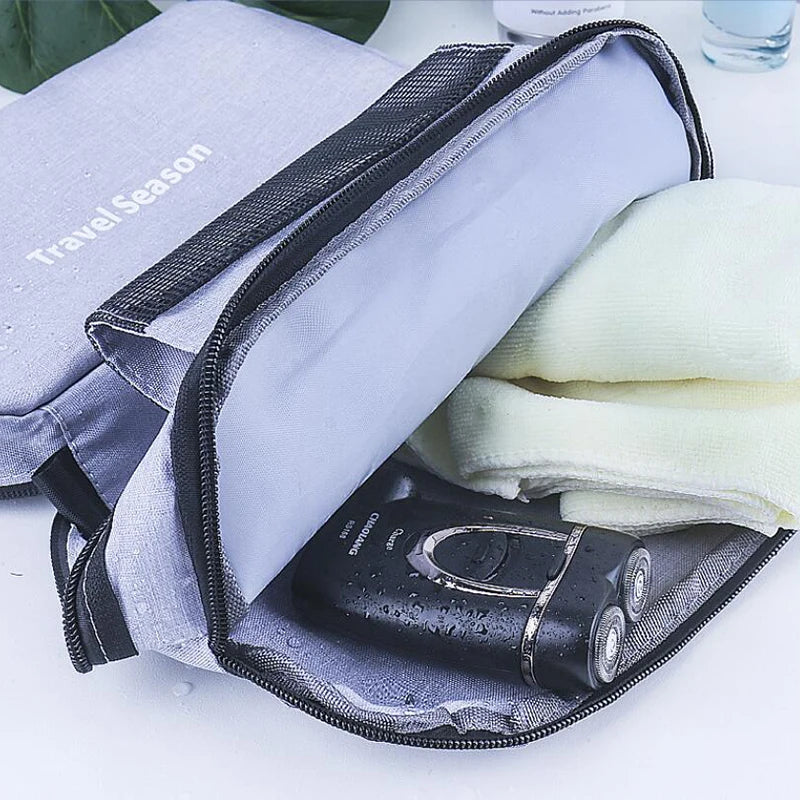 Gray toiletry bag with a razor and towel on a white surface